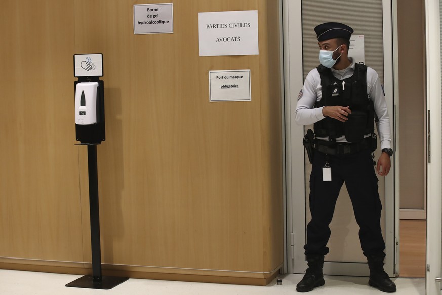 A police officier guards the courtroom at the Paris Hall of Justice Wednesday, Dec. 16, 2020 in Paris. The terrorism trial of 14 people linked to the January 2015 Paris attacks on the satirical weekly ...