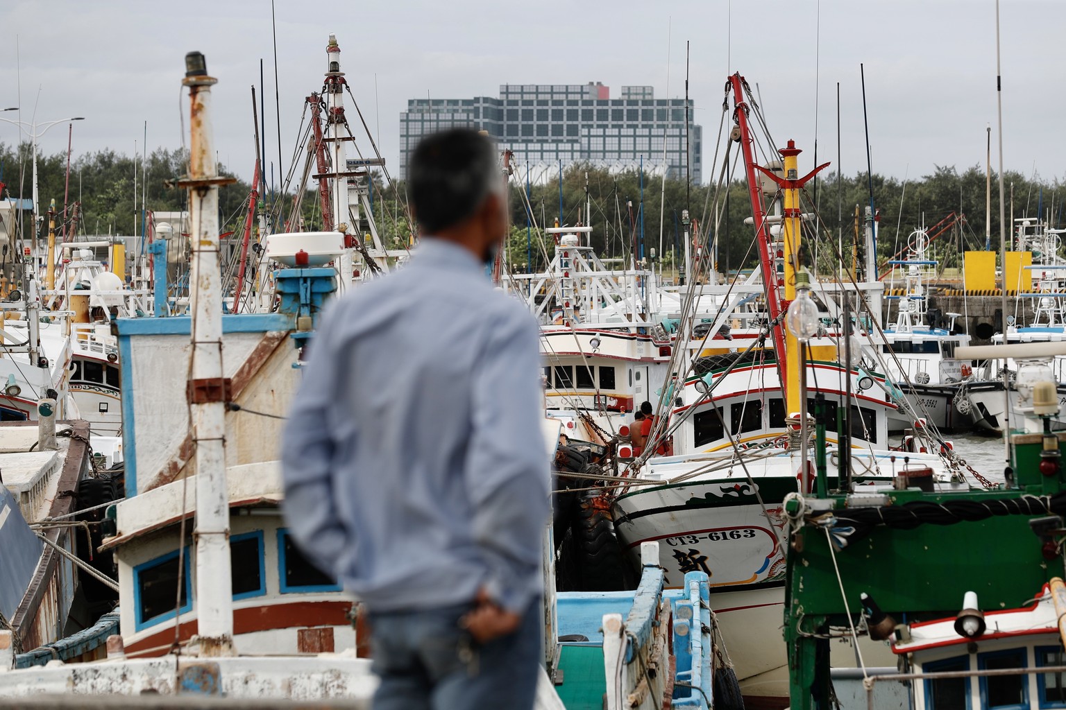 epa10837071 A Taiwanese person inspects fishing boats anchored as a precaution against Typhoon Haikui, at Nanliao Fishing Harbor in Hsinchu, Taiwan, 03 September 2023. Typhoon Haikui moves closer to T ...