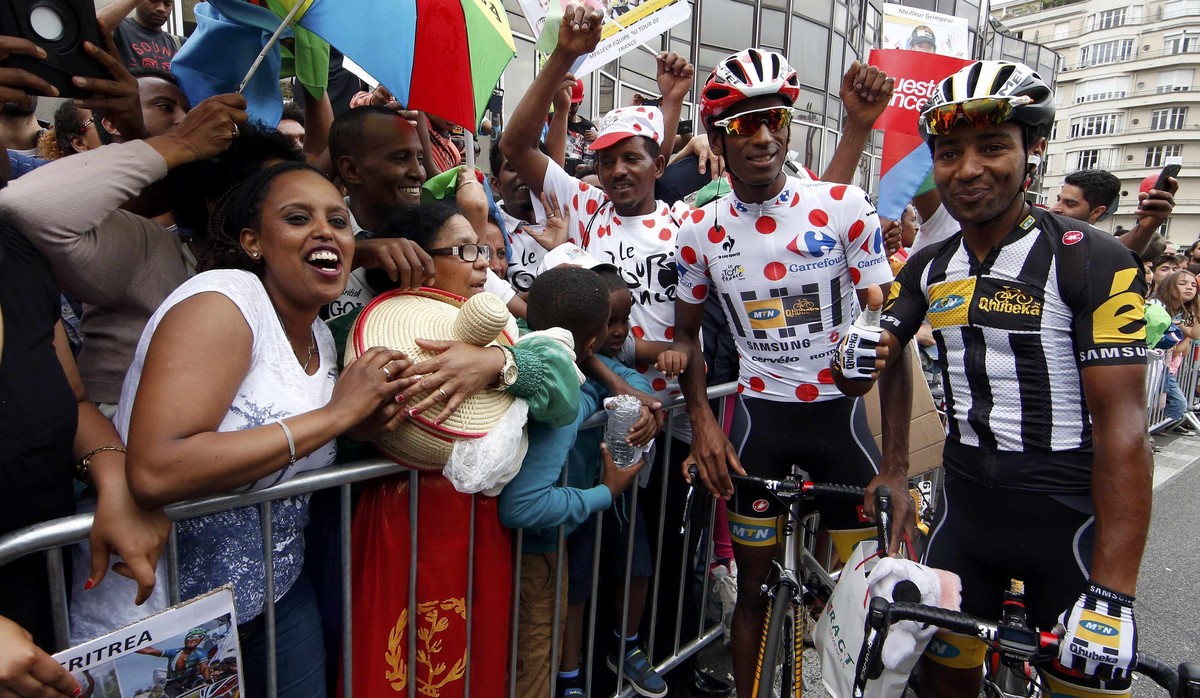 MTN-Qhubeka rider Daniel Teklehaimanot of Eritrea (C), best climber's dotted jersey, and team-mate Merhawi Kudus Ghebremedhin (R) pose with Eritrean supporters before the start of the 181.5-km (1 ...