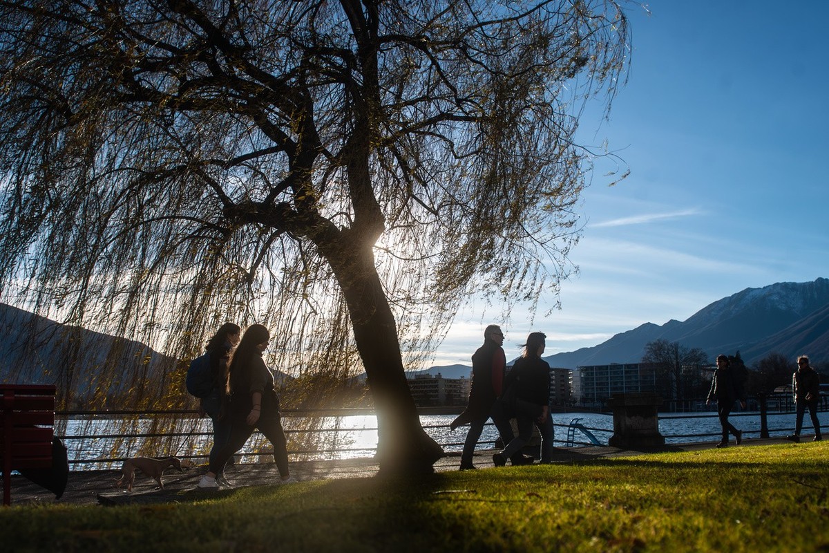 Menschen geniessen an der Seepromenade am Lago Maggiore in Locarno die warmen Temperaturen, aufgenommen am Samstag, 23. Dezember 2023. (KEYSTONE/Ti-Press/Samuel Golay)