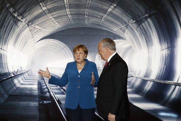 Swiss Federal President Johann Schneider- Ammann, right, listens to German Chancellor Angela Merkel, left, on the opening day of the Gotthard rail tunnel, at the fairground Rynaecht at the northern po ...