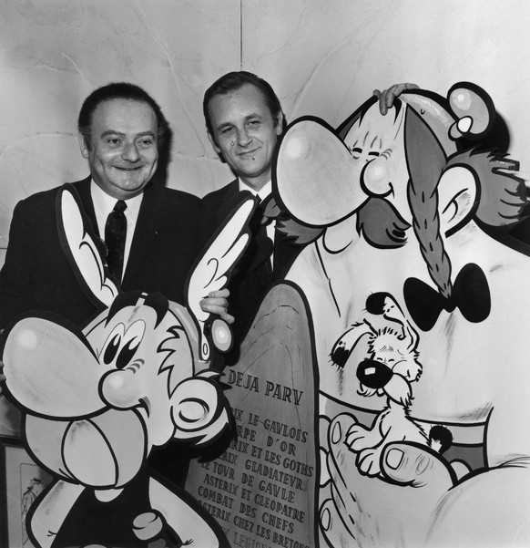FRANCE - NOVEMBER 16: The French Scriptwriter Rene Goscinny And Illustrator Albert Uderzo Holding A Huge Drawing Of The Comic-Strip Heroe Asterix, One Of Its Adventure Was Adapted Into A Movie On Nove ...