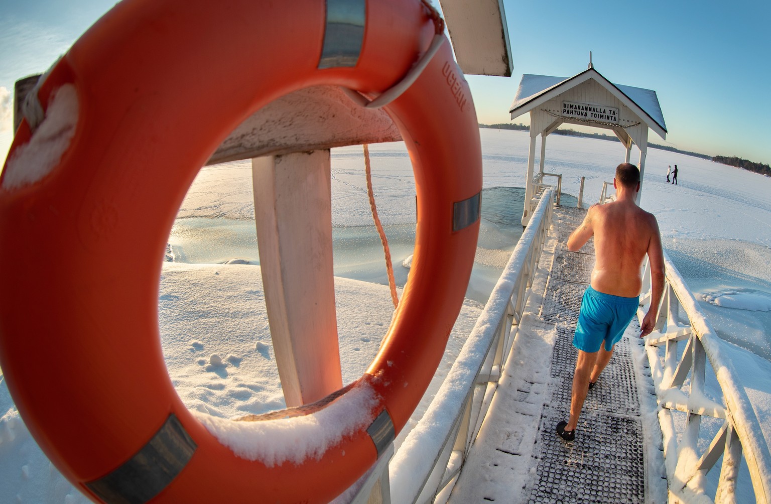 epa08942084 A man walks into a cold ice water after sauna in Helsinki, Finland, 16 January 2021. Temperatures in the capital of Finland may drop to minus 17 degrees Celsius in the night. EPA/MAURI RAT ...