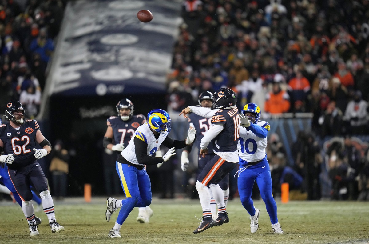 Chicago Bears quarterback Caleb Williams (18) throws a touchdown pass to tight end Cole Kmet, not visible, as Los Angeles Rams linebacker Josaiah Stewart (10) and linebacker Jared Verse (8) apply pres ...