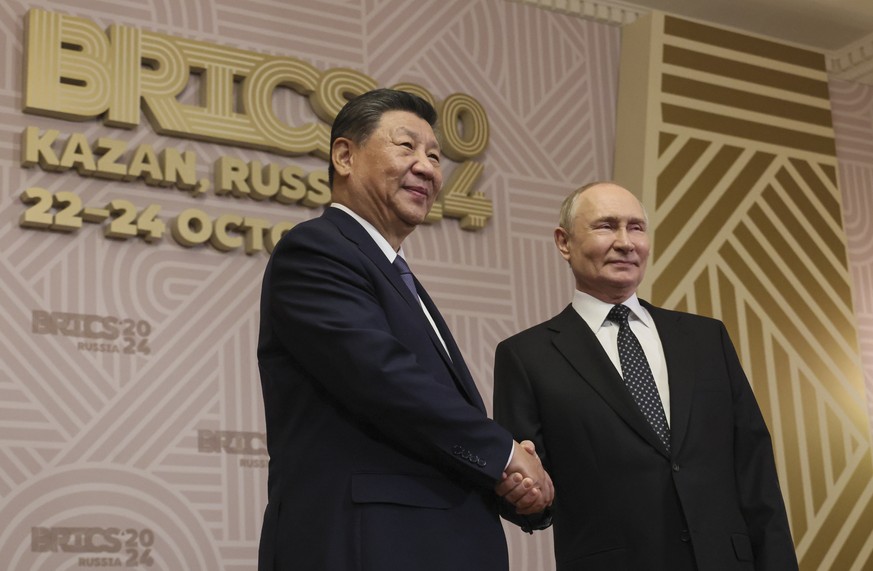 epa11675347 Russian President Vladimir Putin (R) shakes hands with Chinese President Xi Jinping during a welcoming ceremony before an informal dinner on sidelines of the BRICS 2024 Summit in Kazan, Ru ...