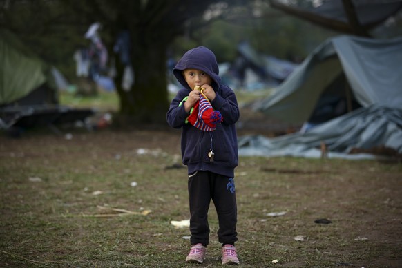 A migrant child eats a banana while posing for a photograph at a makeshift camp housing migrants mostly from Afghanistan, in Velika Kladusa, Bosnia, Tuesday, Oct. 12, 2021. Dozens of children of all a ...