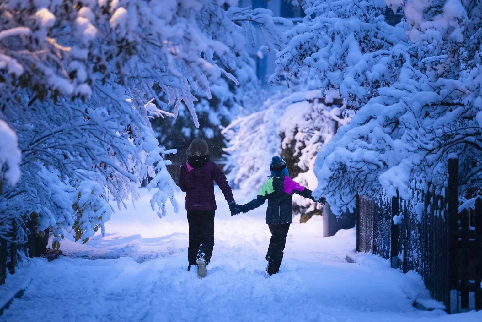 Two kids walk along a path during the season&#039;s first snow fall in Zurich, Switzerland, on Saturday, December 2, 2023. (KEYSTONE/Michael Buholzer)