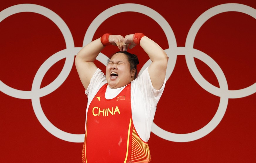 epa09388092 Li Wenwen of China reacts after she breaks Olympic Record lifting 180kg in the third attempt during the Clean &amp; Jerk portion of the Women&#039;s +87kg Group A Gold Medal event of the W ...