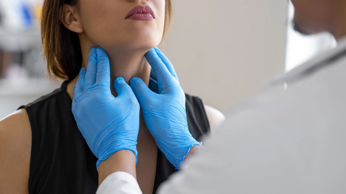 Der Arzt tastet die Schilddrüsen der Patientin ab, um mögliche Erkrankungen festzustellen.