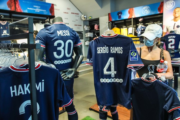 epa09410768 Jerseys of Paris Saint-Germain (PSG) players Achraf Hakimi, Sergio Ramos and Lionel Messi on display for sale at the official PSG store in the Champs Elysee avenue in Paris, France, 12 Aug ...