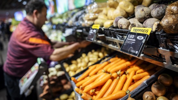 Ein Mitarbeiter raeumt Gemuese ein, neben einem Schild mit der Aufschrift "Tiefpreis" in der Migros Limmatplatz, aufgenommen anlaesslich einer Medienkonferenz zu Neuerungen in den Migros-Sup ...