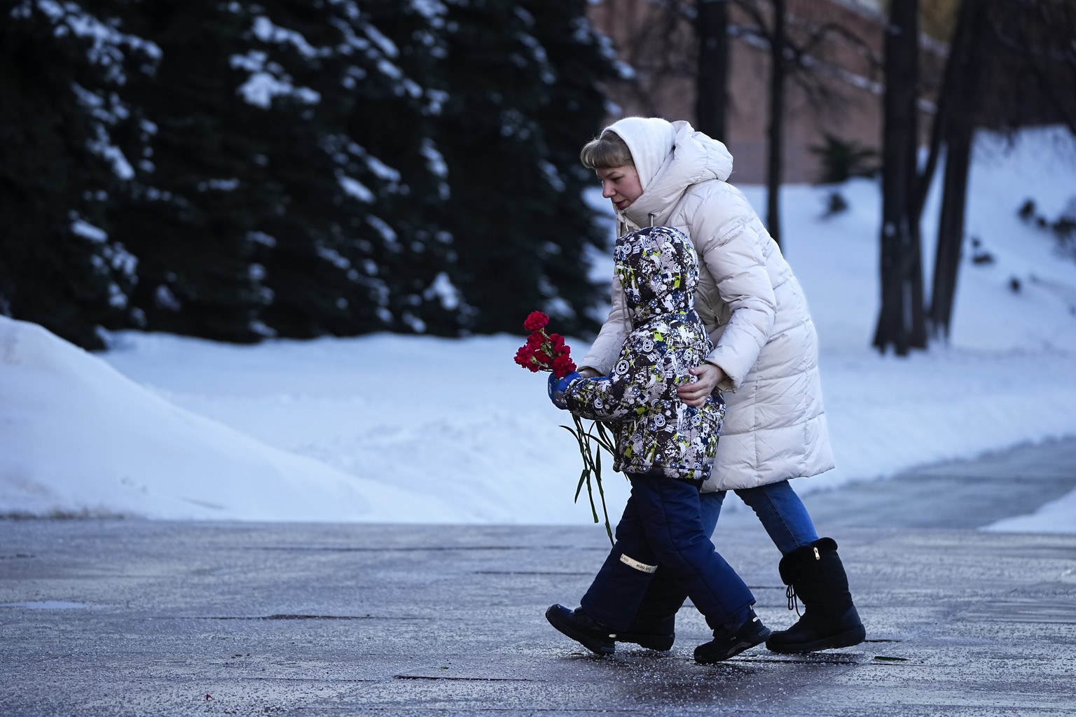 One of wives of Russian soldiers mobilized for fighting in Ukraine walks with her child to lay flowers at the Unknown Soldier&#039;s Tomb at the Kremlin wall in Moscow, Russia, Saturday, Jan. 13, 2024 ...