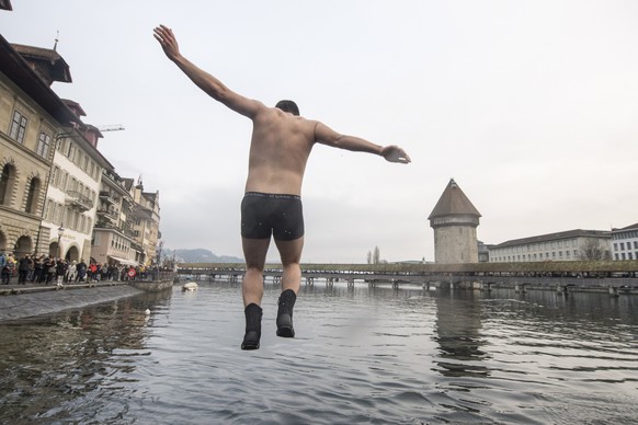 epa07255586 One of approximately 40 lifeguards and swimmers of the Swiss Life Saving Society SLRG Lucerne Section celebrates New Year&#039;s Eve together with a jump into the Reuss river in the old to ...