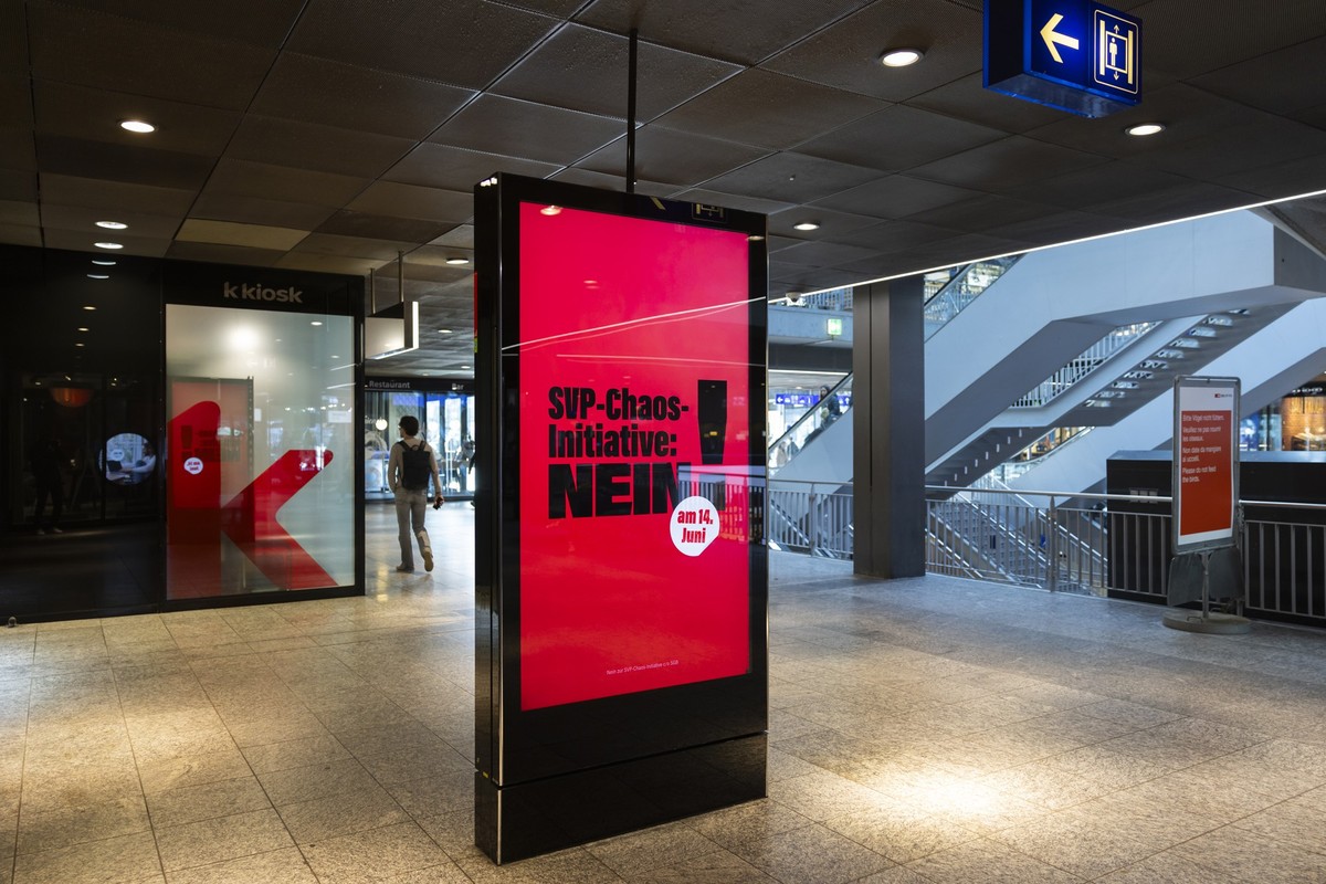 Eine Anzeige des Schweizer Gewerkschaftsbundes (SGB) fuer ein "Nein zur SVP-Chaos-Initiative am 14. Juni 2026" wird auf einem Bildschirm angezeigt, am Mittwoch, 4. Maerz 2026, im Hauptbahnho ...