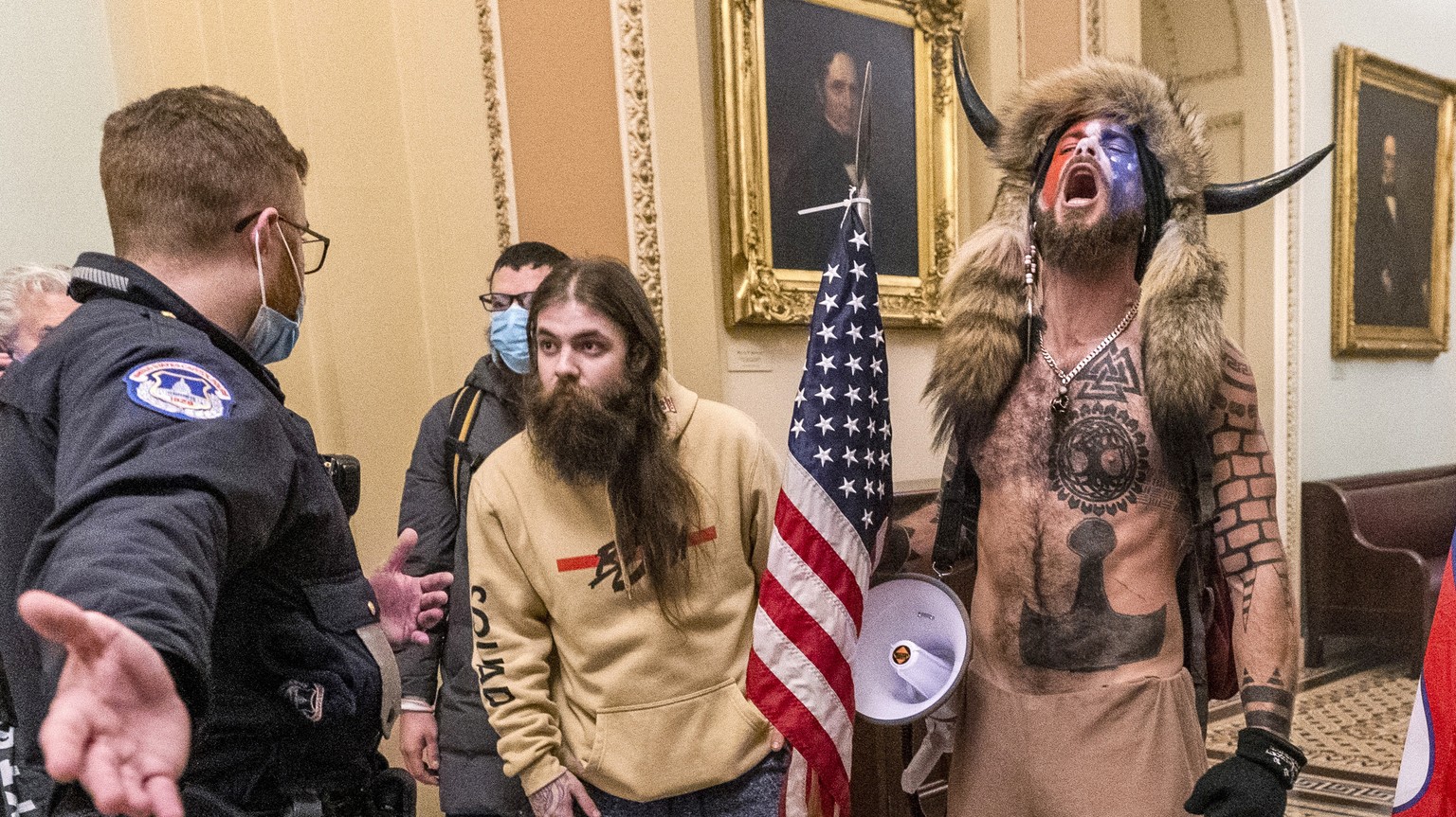 FILE - In this Wednesday, Jan. 6, 2021 file photo, supporters of President Donald Trump, including Jacob Chansley, right with fur hat, are confronted by U.S. Capitol Police officers outside the Senate ...