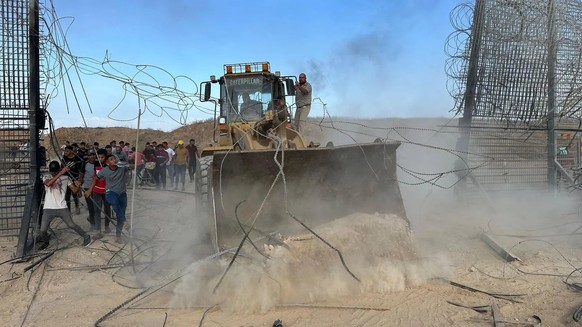 Hamas supporters cross the border fence with Israel with an excavator in Khan Yunis in the southern Gaza Strip.