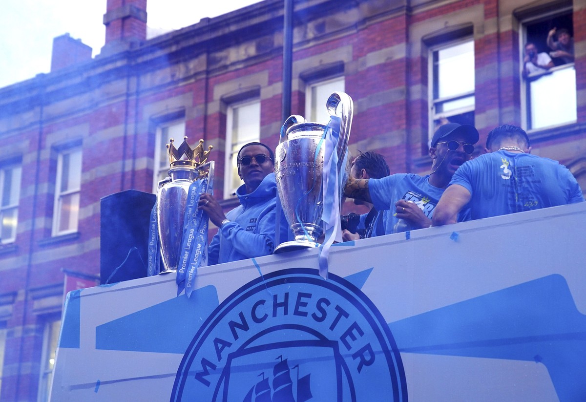 Manchester City's Manuel Akanji, left, with the Premier League trophy and Kyle Walker with the Champions League trophy during the parade to celebrate winning the Premier League, FA Cup and Champi ...