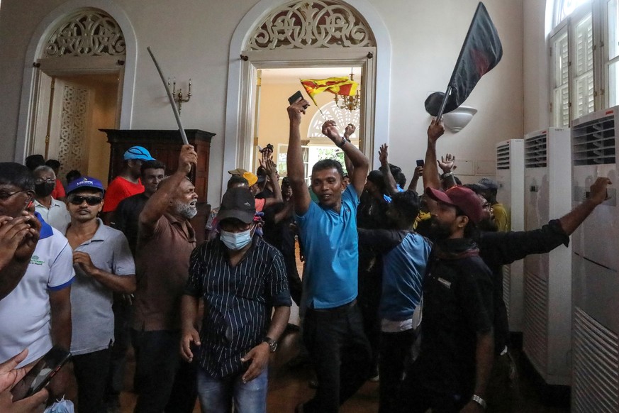 epa10061735 Protesters cheer inside the president&#039;s official residence premises in Colombo, Sri Lanka, 09 July 2022. Thousands of protesters broke through police barricades and stormed the presid ...