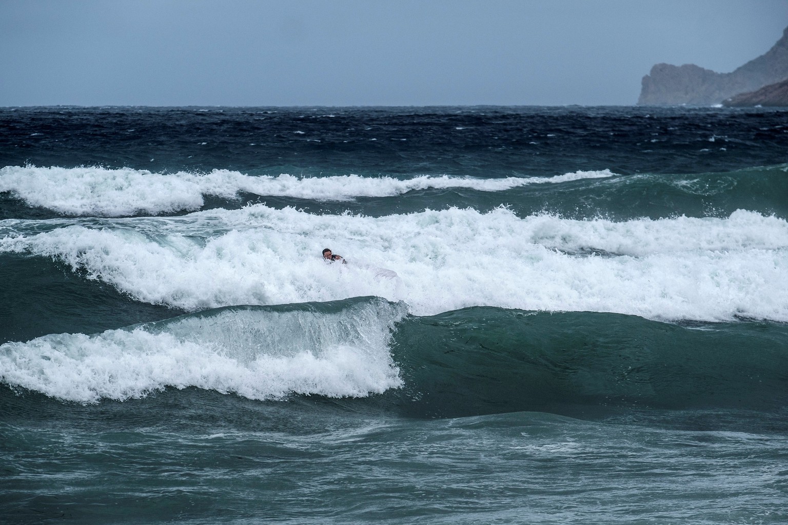 epa08633361 A surfer fights against the waves on a windy day in Bou beach in Sant Josep de Sa Talaia in Ibiza, Balearic Islands, Spain, 29 August 2020. Orange and yellow warnings have been issued in B ...