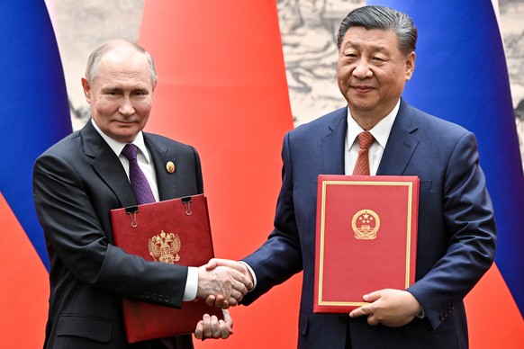 epa11344167 Russian President Vladimir Putin (L) and Chinese President Xi Jinping shake hands as they attend a signing ceremony following a meeting in expanded format at the Great Hall of the People i ...