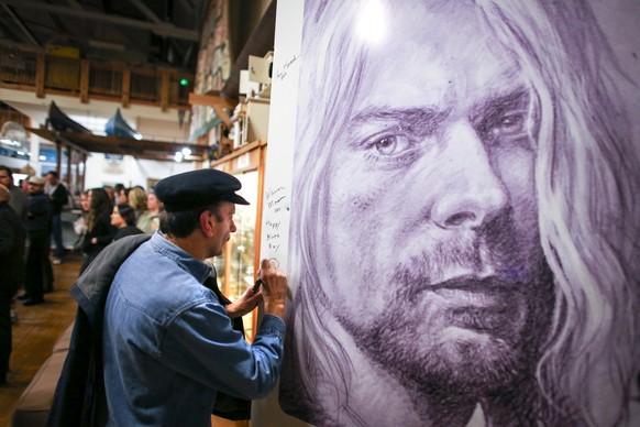 Warren Mason, Kurt Cobain&#039;s first guitar teacher, signs an image of the musician during the first annual Kurt Cobain Day on Thursday, Feb. 20, 2014 in Aberdeen, Wash. The town formally recognized ...