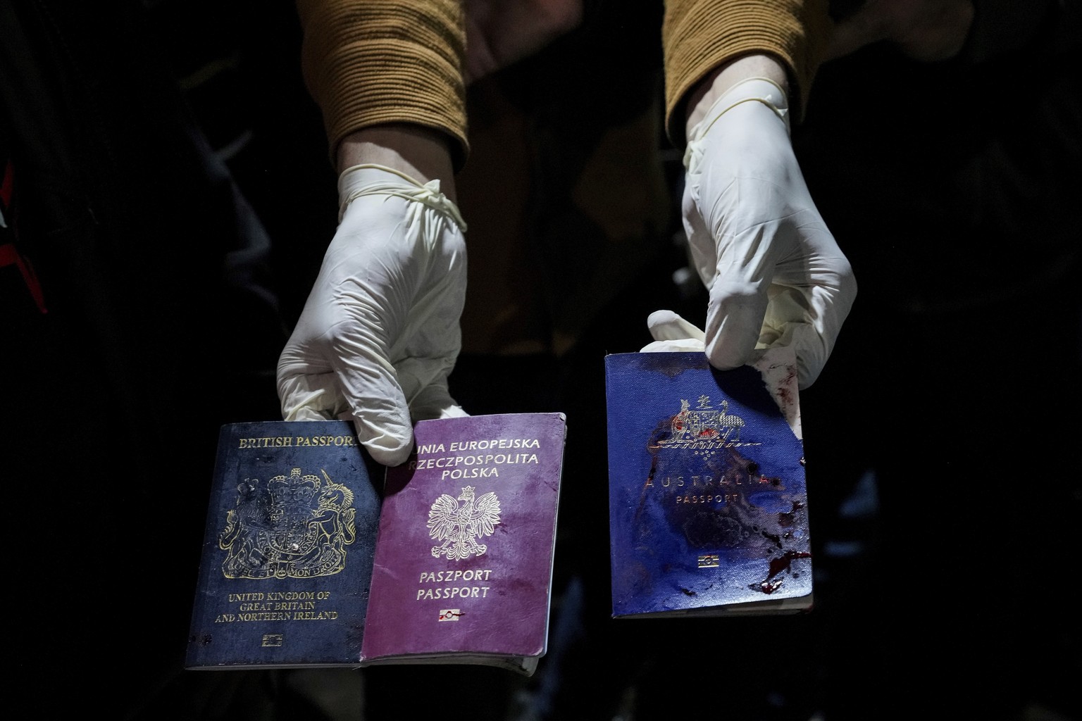 A man displays blood-stained British, Polish, and Australian passports after an Israeli airstrike, in Deir al-Balah, Gaza Strip, Monday, April 1, 2024. Gaza medical officials say an apparent Israeli a ...