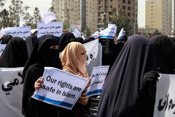 epa09461016 Afghan women hold placards during a pro-Taliban rally outside the Shaheed Rabbani Education University in Kabul, Afghanistan, 11 September 2021. The United States envoy for peace in Afghan ...