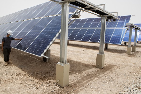 A worker inspects a panel at a solar power plant in the Faiha oil field east of Basra, Iraq, Monday, June 27, 2022. (AP Photo/Nabil al-Jurani)