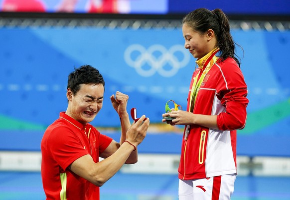 epa05485088 He Zi (R) of China receives a marriage proposal from Chinese diver Ki Qin (L) after winning the silver medal in the women&#039;s 3m Springboard final of the Rio 2016 Olympic Games Diving e ...