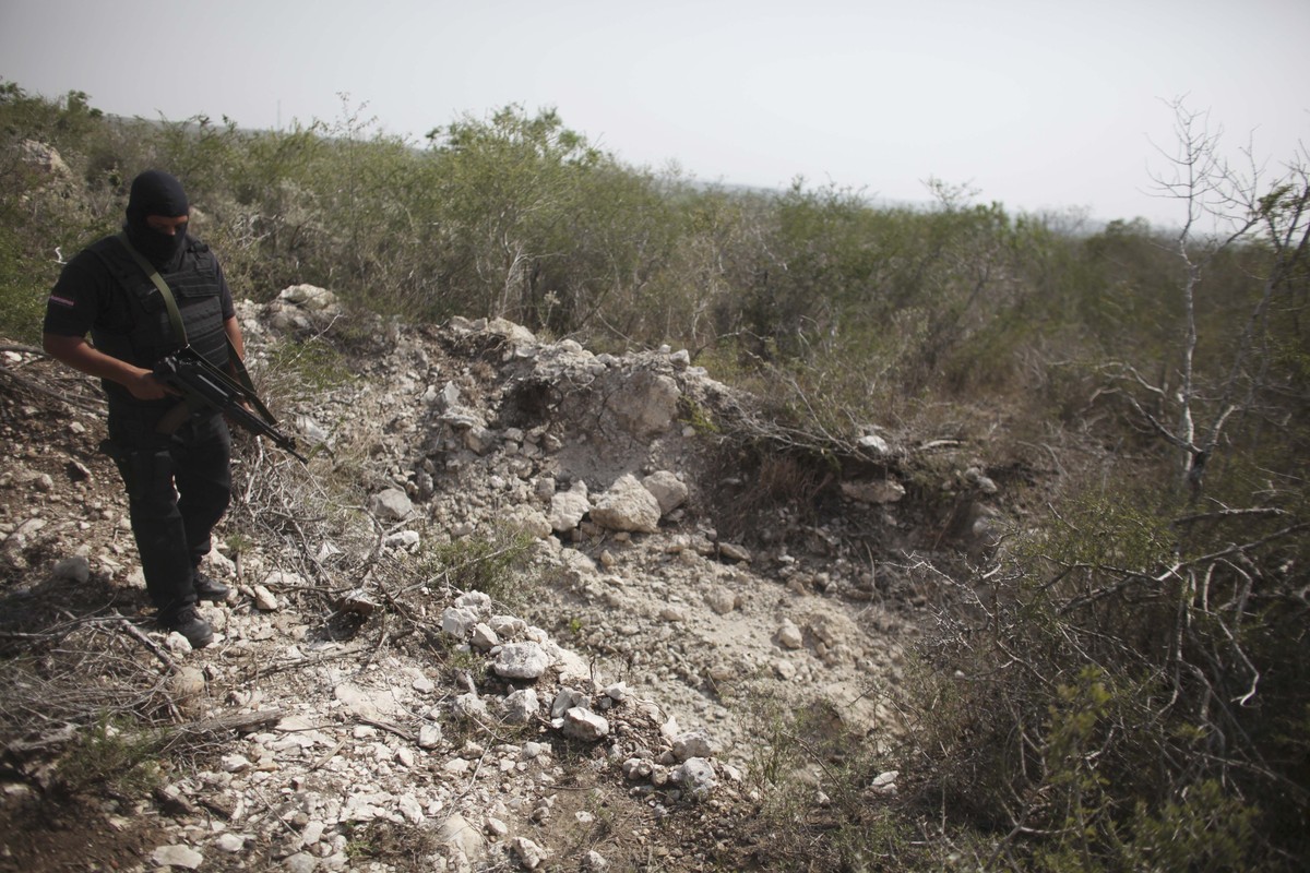 FILE - An officer walks past a hole that police say was used as a mass grave, near San Fernando, Tamaulipas state, Mexico, April 27, 2011. The body of 17-year-old Guatemalan Yovanny was found among ne ...