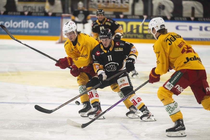 Marco Zanetti (HCL), center, fight for the puck with Jiri Felcman (SCL), left and Tim Mathys (SCL), right, during the regular season of National League Swiss Championship 2025/26 between HC Lugano and ...