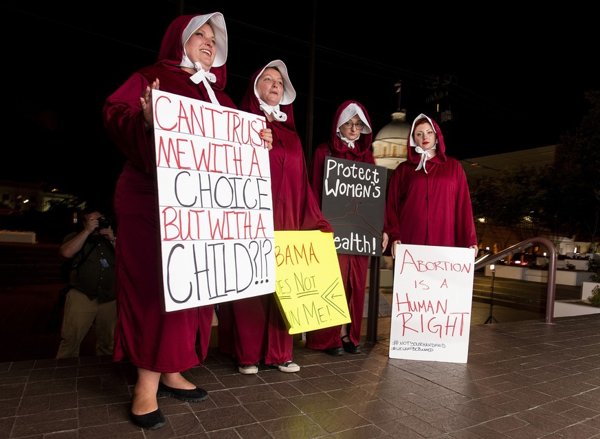 Protesters, dressed as handmaids, from left, Bianca Cameron-Schwiesow, Kari Crowe, Allie Curlette and Margeaux Hartline, wait outside of the Alabama statehouse after a ban on nearly all abortions pass ...