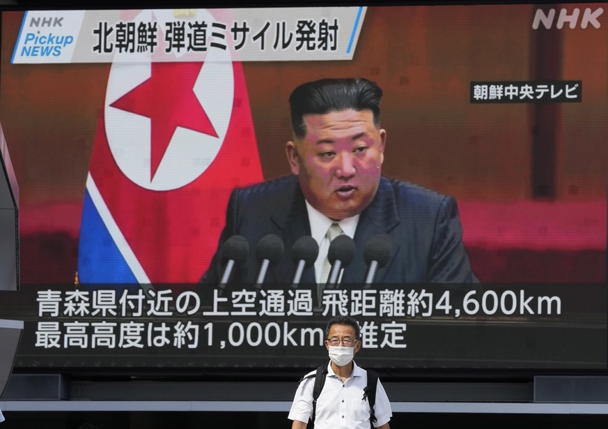epa10222149 A pedestrian walks under a huge screen displaying news reporting North Korea's missile launch, featuring an image of North Korean Leader Kim Jong-un, in Tokyo, Japan, 04 October 2022. Nort ...
