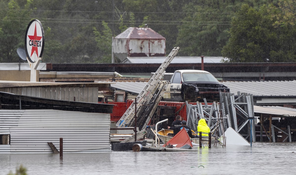 Men paddle through flooded waters to inspect submerged buildings at Londonderry on the western outskirts of Sydney Monday, March 22, 2021. Hundreds of people have been rescued from floodwaters that ha ...
