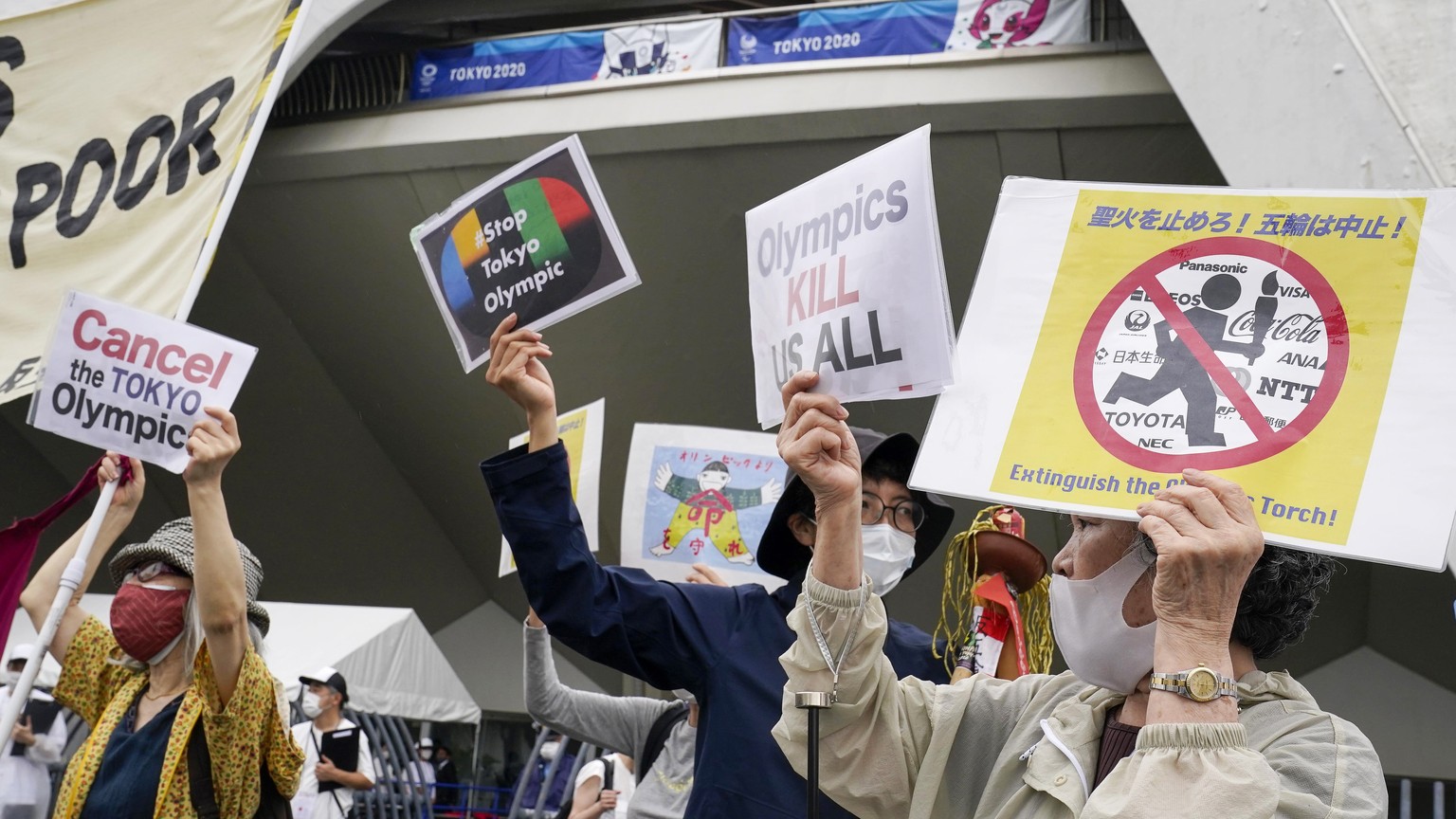 epa09332737 Demonstrators protest against the Tokyo 2020 Olympics outside the venue of the unveiling ceremony for the Olympic Flame of the Tokyo 2020 Olympic Torch Relay at the Komazawa Olympic Park G ...