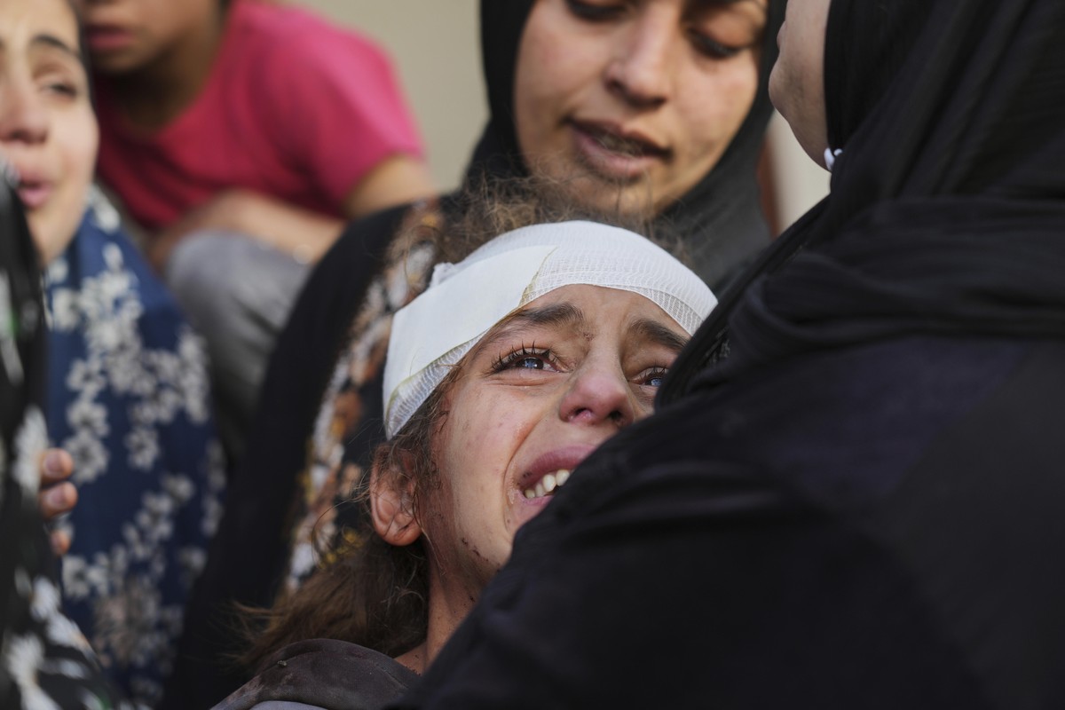 Yamama Jundia, 13, injured in an Israeli airstrike, grieves alongside others over the bodies of their relatives, who were killed in the same strike, at the Baptist Hospital in Gaza City on Thursday, A ...