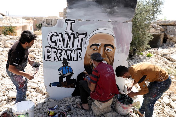 epa08458370 Syrians spray graffiti to honor the killed US man George Floyd on the wall of a house destroyed by war, Idlib, Syria, 01 June 2020. A bystander's video posted online on 25 May appeare ...