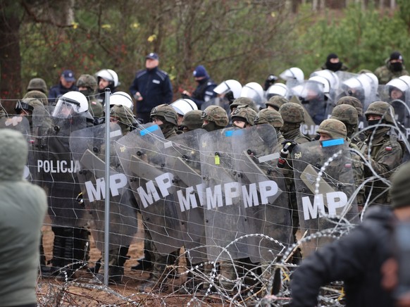 epa09572071 A handout photo made available by Belta news agency shows Polish authorities taking position as migrants gather on the Belarusian-Polish border in the Grodno region, Belarus, 08 November 2 ...
