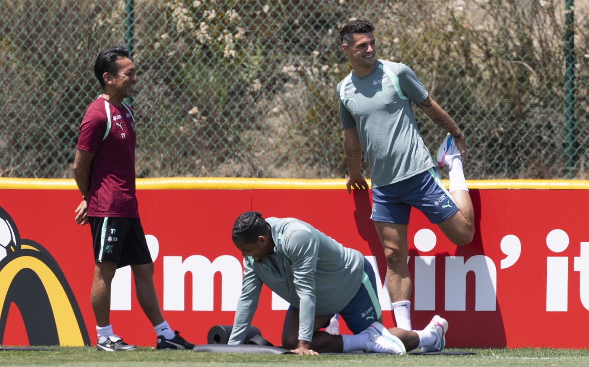 Switzerland's Granit Xhaka, right, and Manuel Akanji exercise stretching next to physio therapist Takahiro Yamamoto, left, during a training session of the Swiss national soccer team at the SDJA  ...