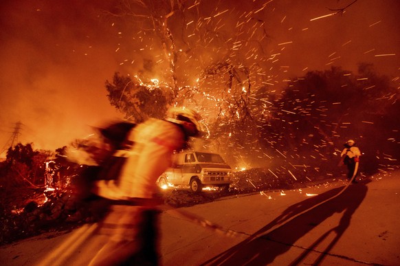 FILE - In this Dec. 3, 2020 file photo Firefighters battling the Bond Fire haul a hose while working to save a home in the Silverado community in Orange County, Calif. California&#039;s U.S. senators  ...