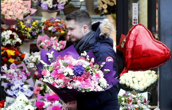 epa11152364 A man holds flowers and a heart balloon on Valentine&#039;s Day in Riga, Latvia, 14 February 2024. Valentine&#039;s Day, a day dedicated to expressing love with romantic gestures, is celeb ...