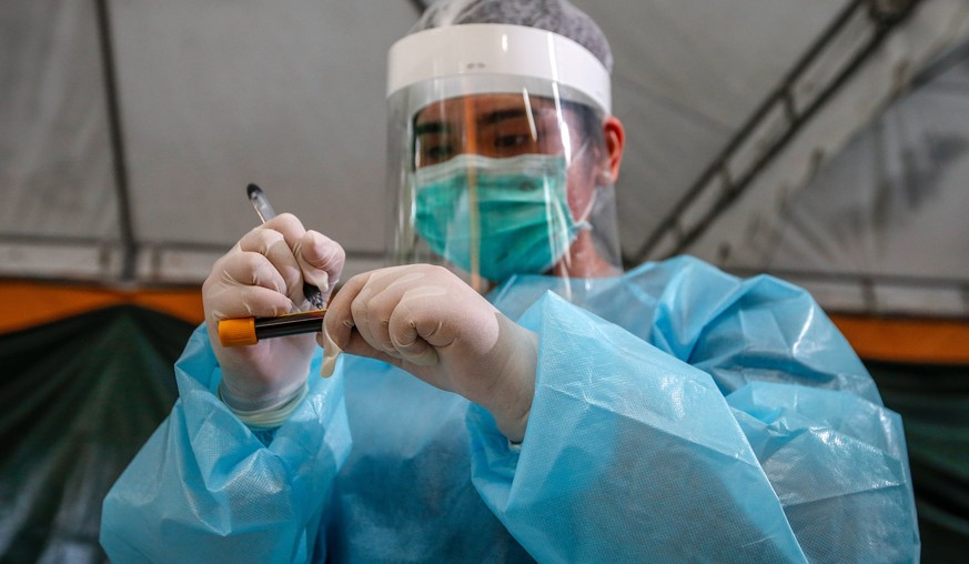 epa08531964 A health worker writes on a blood vial after performing an Enhanced Chemiluminescence Immunoassay (ECLIA) antibody test on a man at a drive-thru COVID-19 testing facility at the Medical Ci ...