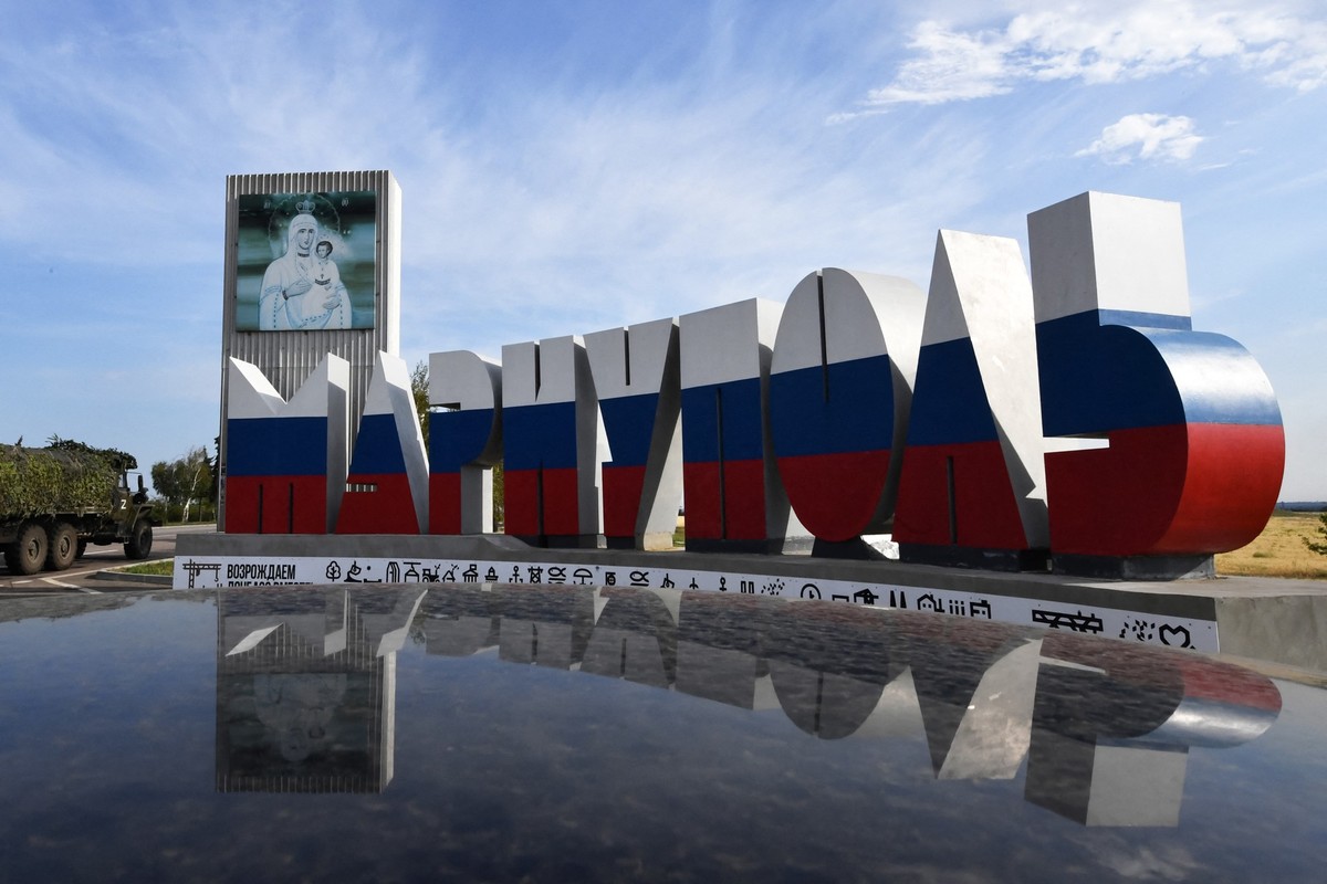 A Russian military truck passes a road sign reading "Mariupol" and painted in the colours of the Russian national tricolor flag in the Russian-controlled Azov Sea port city of Mariupol in so ...