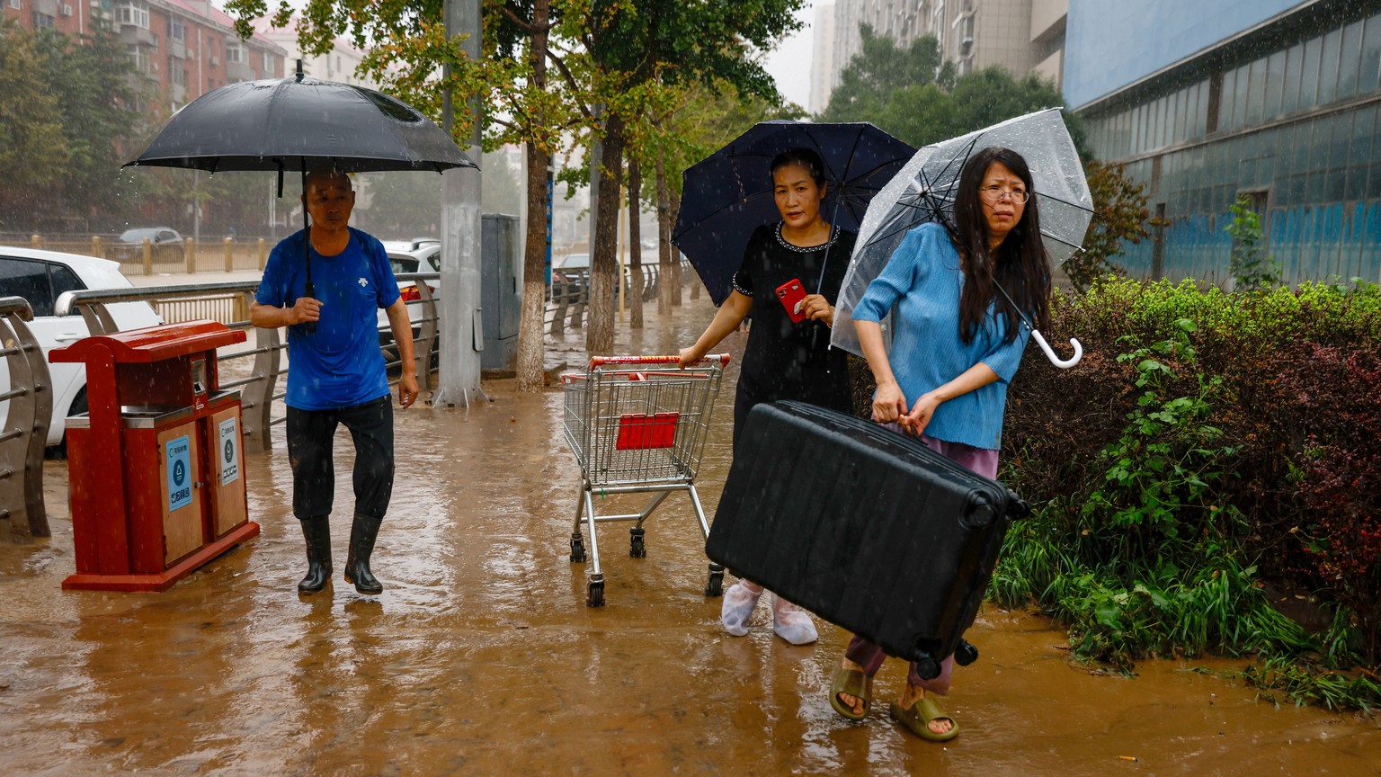 epa10779162 A woman carries her belongings during a downpour in Mentougou District, west of Beijing, China, 01 August 2023. Heavy rains brought by Typhoon Doksuri caused floods in northern China and l ...