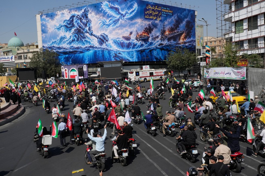 Motorcyclists drive past a billboard depicting a Persian legendary hero and flying figure hitting U.S. aircraft carriers alongside the message in English and Farsi: "From the Persian Gulf a new p ...