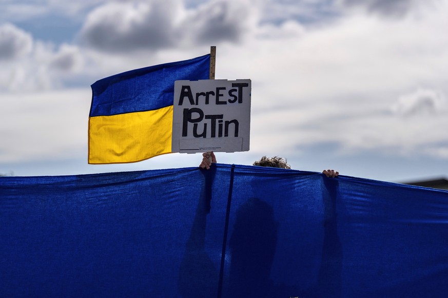 A protester holds a Ukrainian flag and a sign during a rally in Anchorage, Alaska, Thursday, Aug. 14, 2025, ahead of a meeting between President Donald Trump and Russian President Vladimir Putin. (AP  ...