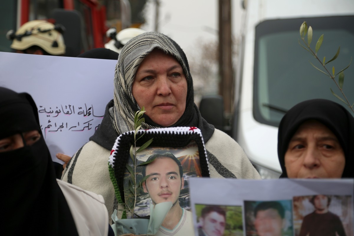 epa11790497 A Syrian woman holds a portrait of her missing loved one during a protest march demanding justice for the detained and disappeared persons during the al-Assad regime, in Syria, in Idlib, n ...
