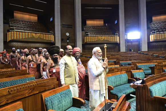 Indian Prime Minister Narendra Modi carries a royal golden scepter to install it at the speaker's seat at the start of the opening ceremony of the new parliament building, in New De…