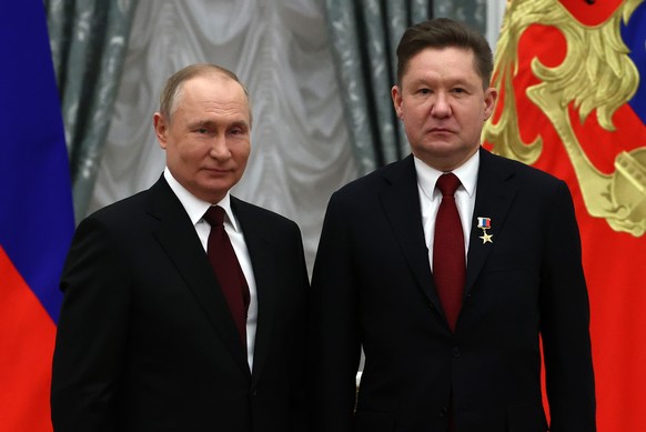 epa09723113 Russian President Vladimir Putin (L) and Chairman of Gazprom Management Committee Alexei Miller (R), who was awarded the Hero of Labor of the Russian Federation title, pose for a photograp ...