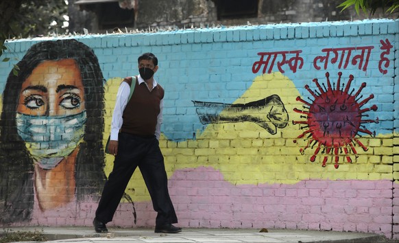 epa08804147 An Indian man passes by a mural on a wall to spread awareness about wearing a protective face mask to avoid spread of  novel coronavirus in New Delhi, India, 07 November 2020. According to reports, India became the second worst-hit country by the spread of novel coronavirus which causes Covid-19 disease, as Indian tally rose to over 8.3 million cases, only behind the United States.  EPA/RAJAT GUPTA